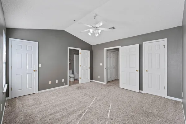 a view of an empty room with chandelier fan and a window