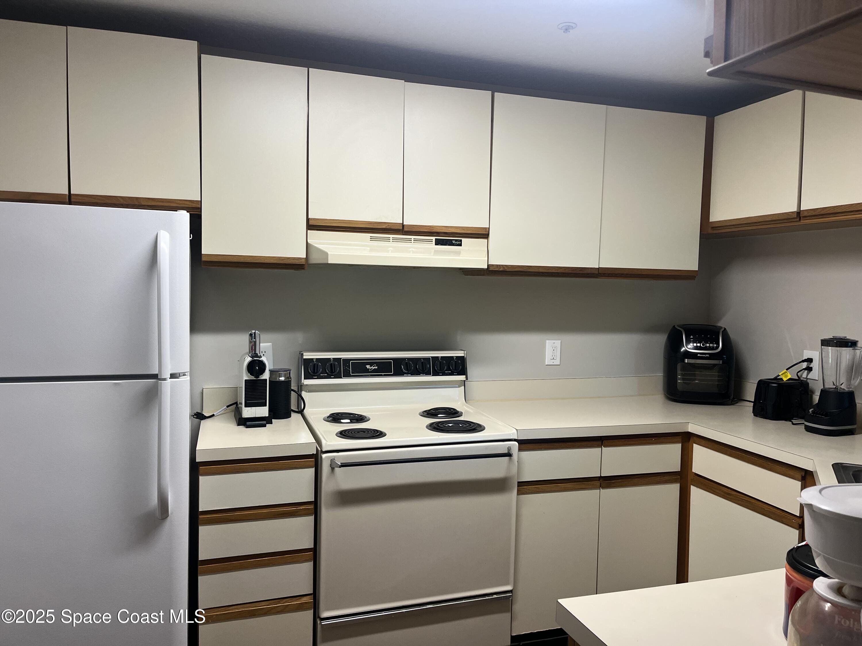 7667 North Wickham Road, Unit 1118 Melbourne, FL 32940 - Photo 2 of 17 a kitchen with a refrigerator and cabinets