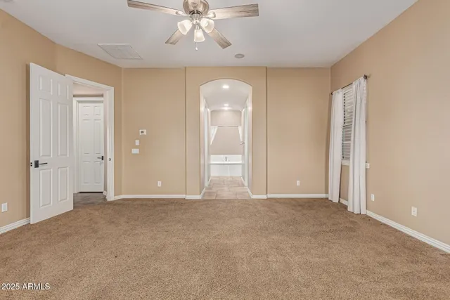 an empty room with chandelier fan and glass door