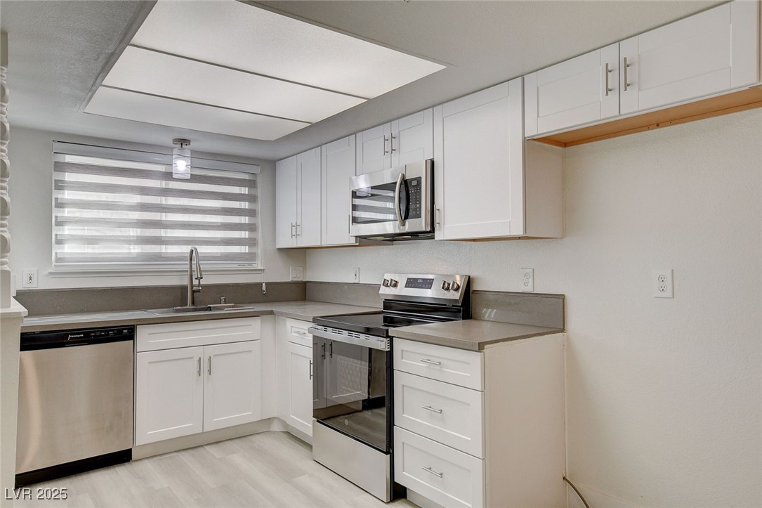 579 Roxella Lane, Unit B Las Vegas, NV 89110 - Photo 14 of 28 Kitchen with appliances with stainless steel finishes, white cabinets, light wood-type flooring, and light countertops