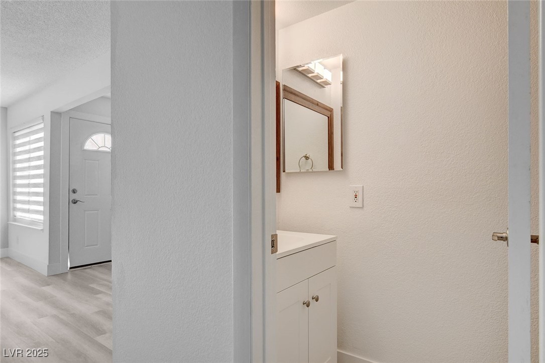 579 Roxella Lane, Unit B Las Vegas, NV 89110 - Photo 15 of 28 Half bath with light wood finished floors, a textured wall, vanity, and a textured ceiling