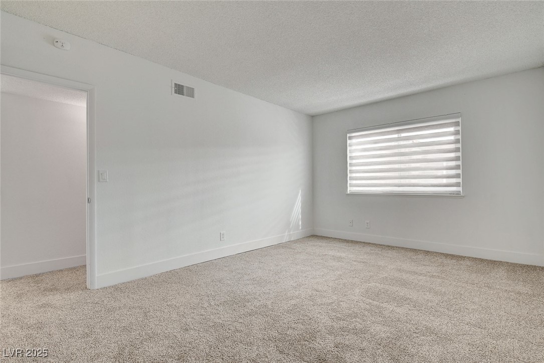 579 Roxella Lane, Unit B Las Vegas, NV 89110 - Photo 19 of 28 Empty room featuring light colored carpet and a textured ceiling