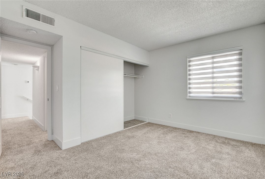 579 Roxella Lane, Unit B Las Vegas, NV 89110 - Photo 22 of 28 Unfurnished bedroom with light carpet, a textured ceiling, and a closet