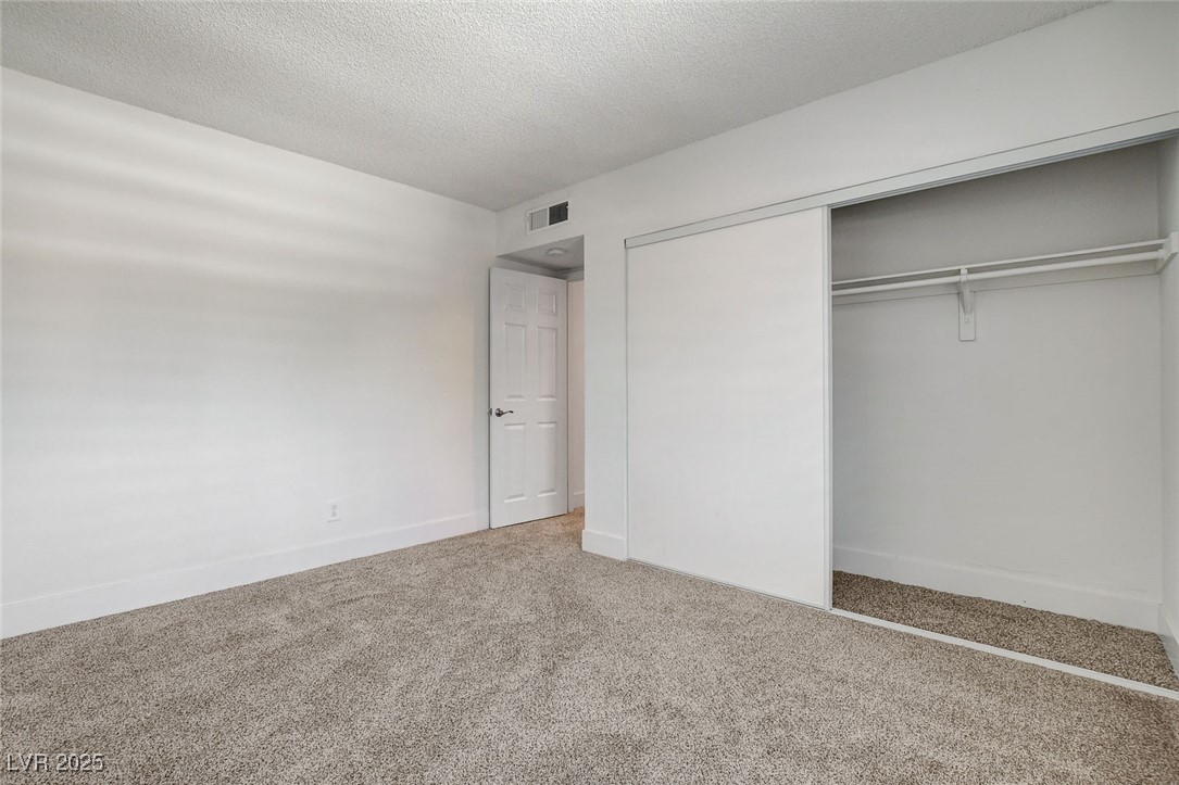 579 Roxella Lane, Unit B Las Vegas, NV 89110 - Photo 23 of 28 Unfurnished bedroom featuring carpet floors, a textured ceiling, and a closet