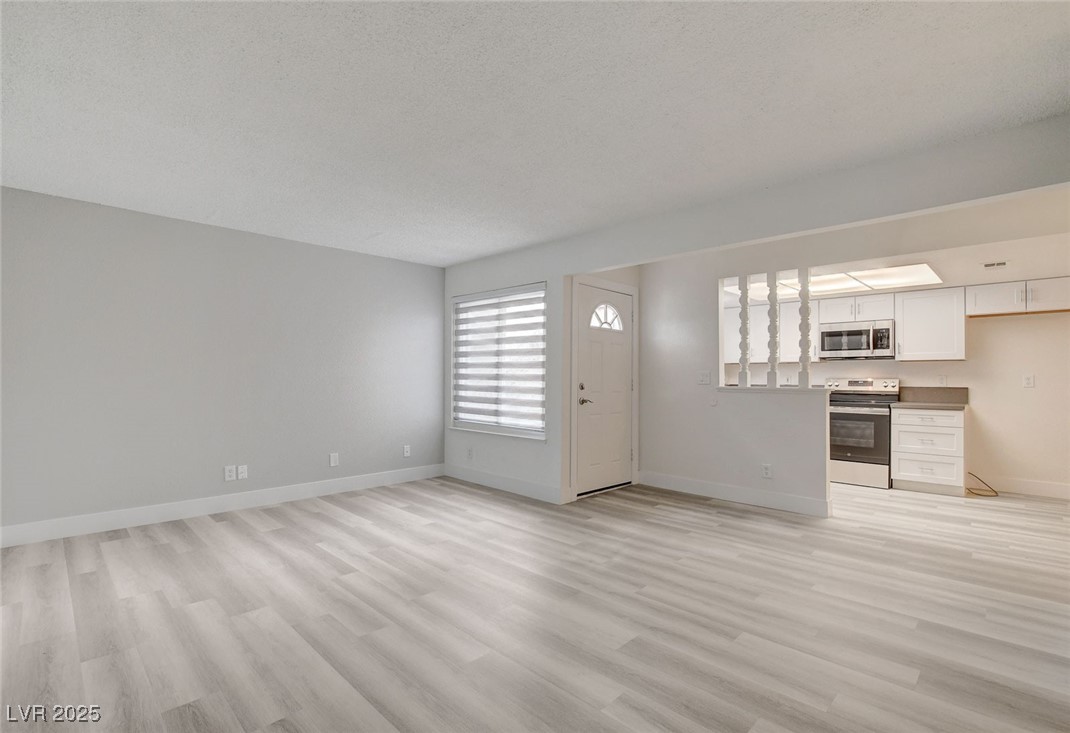 579 Roxella Lane, Unit B Las Vegas, NV 89110 - Photo 4 of 28 Unfurnished living room featuring light wood-type flooring and a textured ceiling