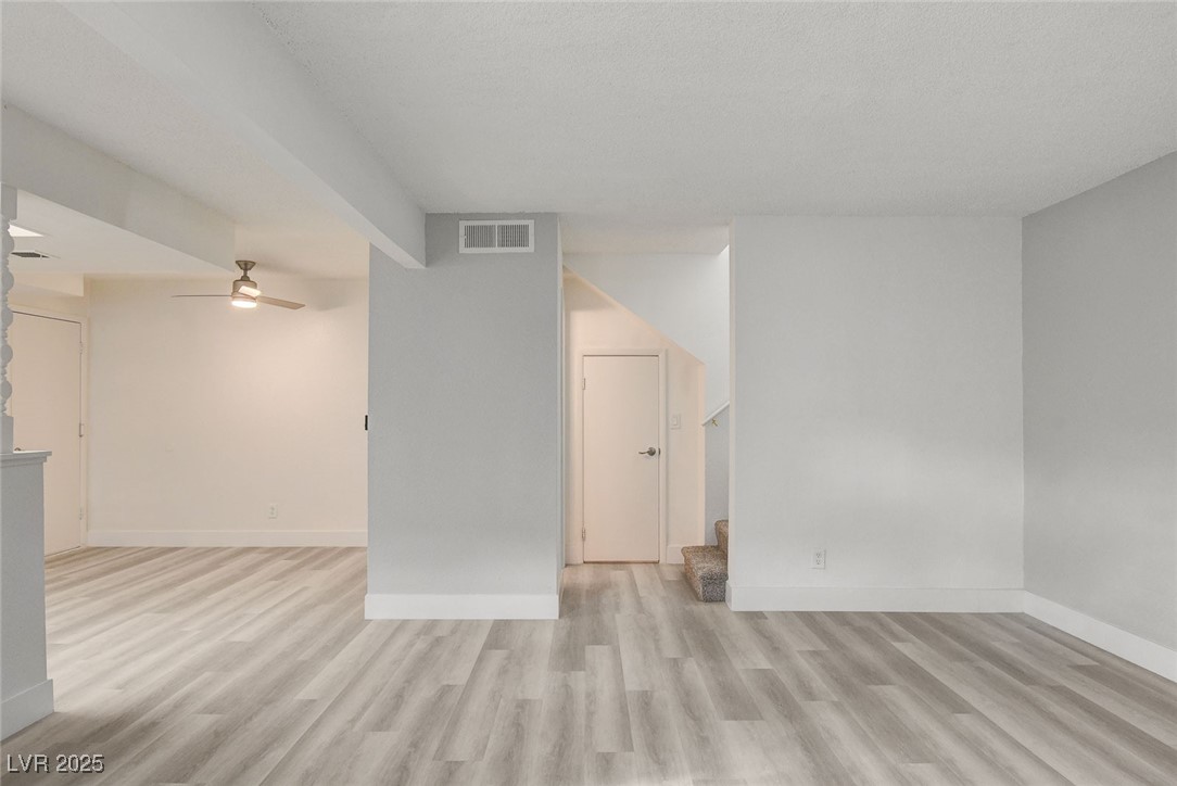 579 Roxella Lane, Unit B Las Vegas, NV 89110 - Photo 6 of 28 Unfurnished living room with ceiling fan, light wood-style floors, and stairs