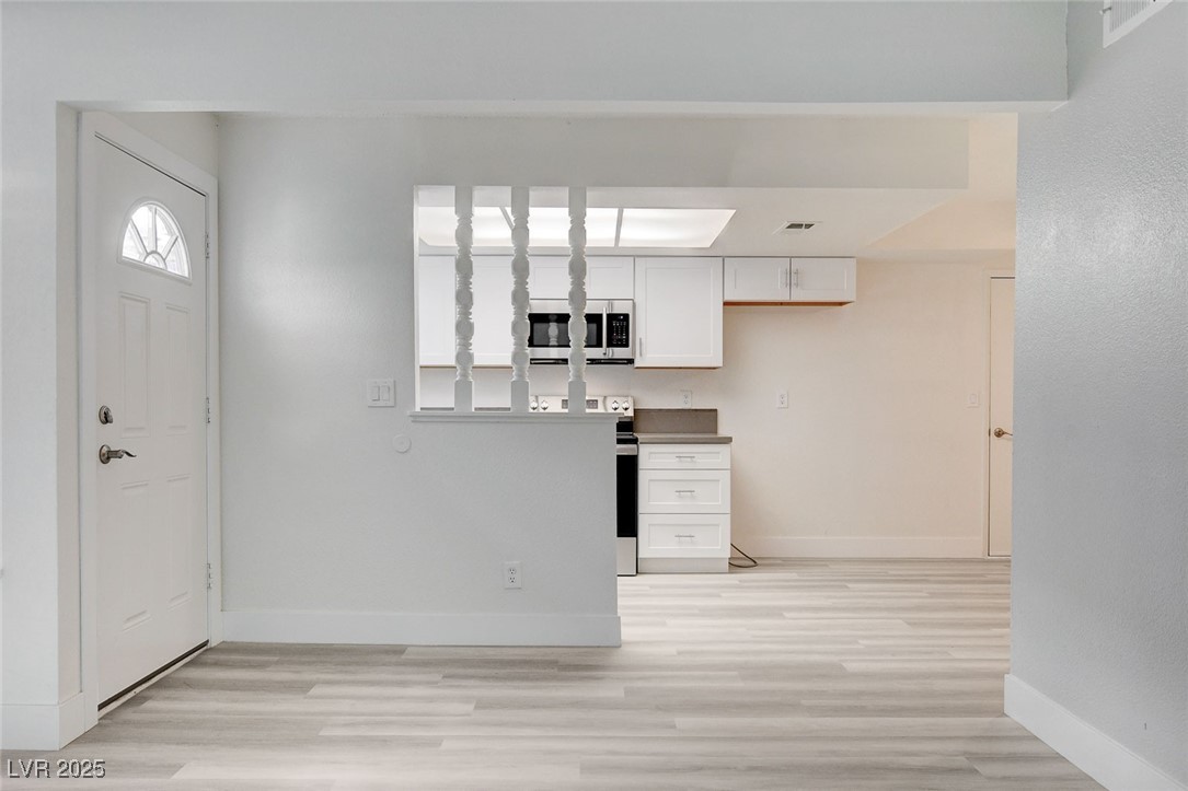 579 Roxella Lane, Unit B Las Vegas, NV 89110 - Photo 7 of 28 Kitchen with white cabinetry, light wood-type flooring, stainless steel microwave, and dark countertops