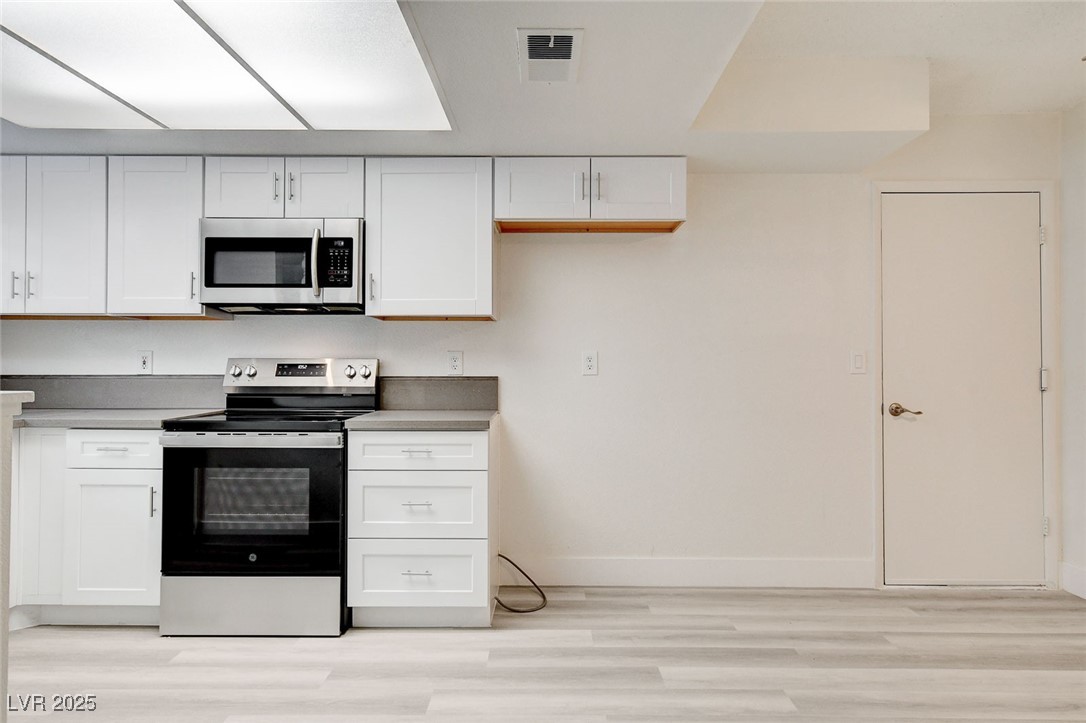 579 Roxella Lane, Unit B Las Vegas, NV 89110 - Photo 9 of 28 Kitchen featuring appliances with stainless steel finishes, white cabinets, and light wood-style flooring