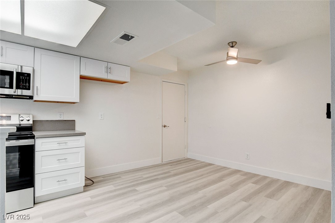 579 Roxella Lane, Unit B Las Vegas, NV 89110 - Photo 10 of 28 Kitchen featuring appliances with stainless steel finishes, white cabinets, light wood finished floors, a ceiling fan, and light countertops