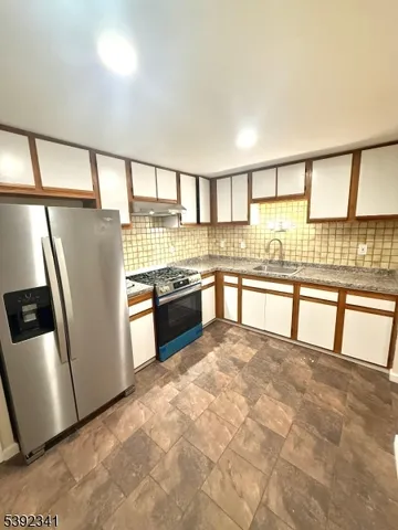 a view of a kitchen with stainless steel appliances granite countertop a stove a sink and a refrigerator