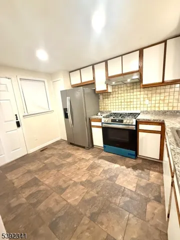 a kitchen with stainless steel appliances granite countertop a refrigerator and a sink