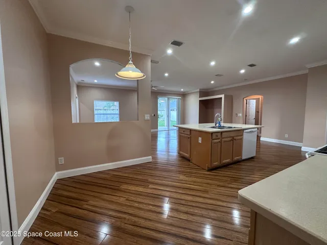 a room with kitchen island a wooden floor and a ceiling fan
