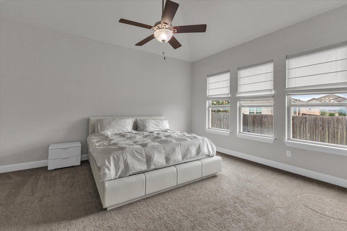 21301 Resource Road Pflugerville, TX 78660 - Photo 10 of 29 Vaulted ceiling with a ceiling fan, three windows with white blinds, neutral carpet flooring, and light gray wall paint