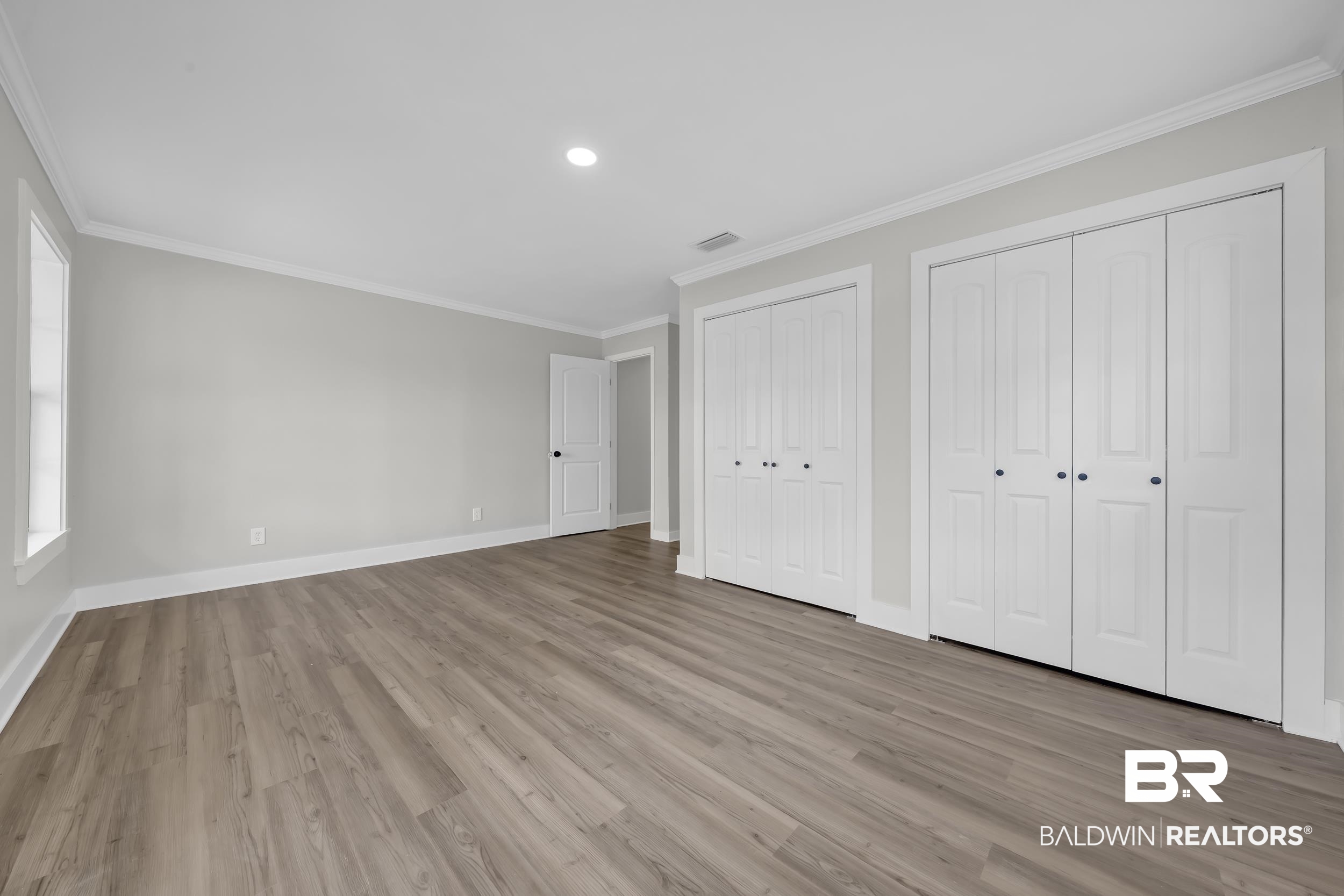 8351 Theodore Dawes Road Theodore, AL 36582 - Photo 18 of 46 Unfurnished bedroom with two closets, ornamental molding, light wood-style floors, and recessed lighting