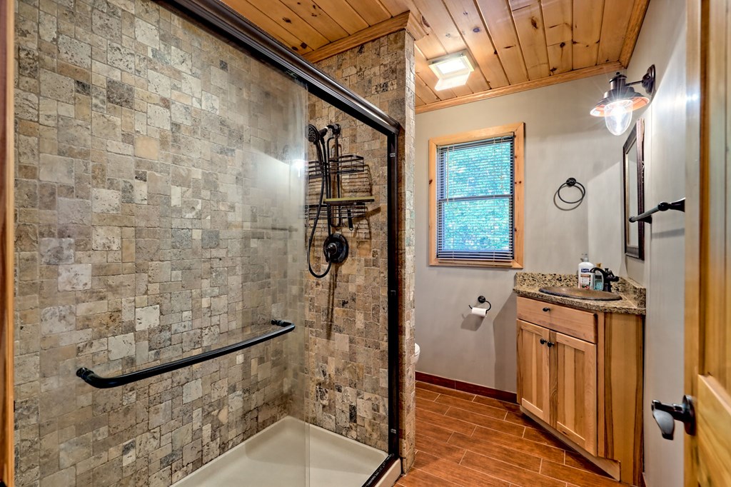 206 Peckerwood Road Hayesville, NC 28904 - Photo 36 of 73 a bathroom with a granite countertop shower a mirror and a sink
