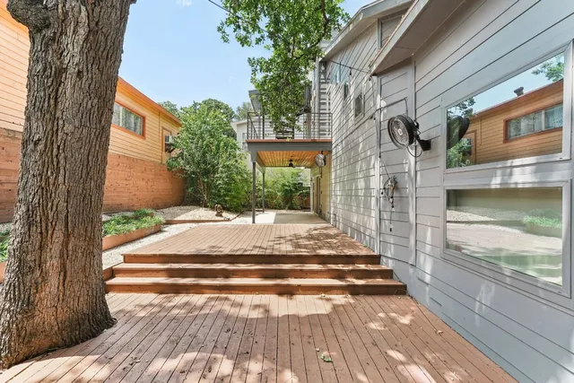 a view of a deck with wooden floor and bench next to a yard