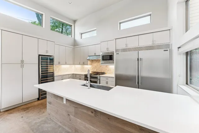 a kitchen with kitchen island a counter top space a sink stainless steel appliances and cabinets