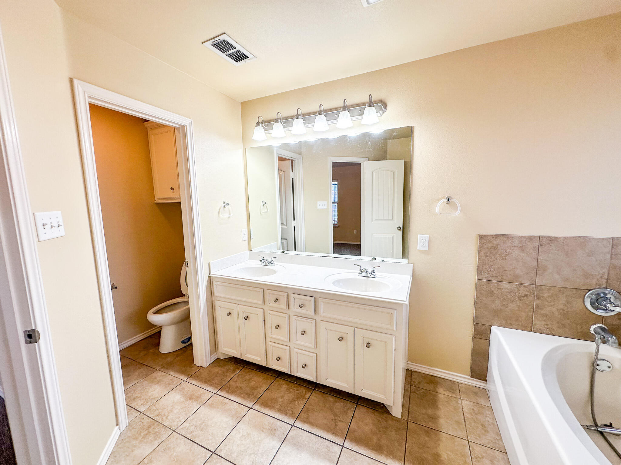 2309 101st Street Lubbock, TX 79423 - Photo 25 of 36 a bathroom with a double vanity sink a toilet and a tub