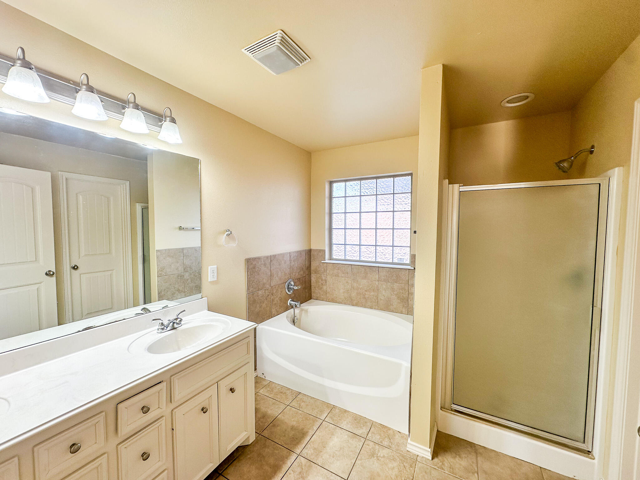 2309 101st Street Lubbock, TX 79423 - Photo 28 of 36 a bathroom with a tub sink shower and a mirror