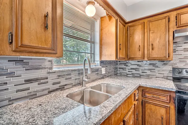 a kitchen with granite countertop sink stove and cabinets