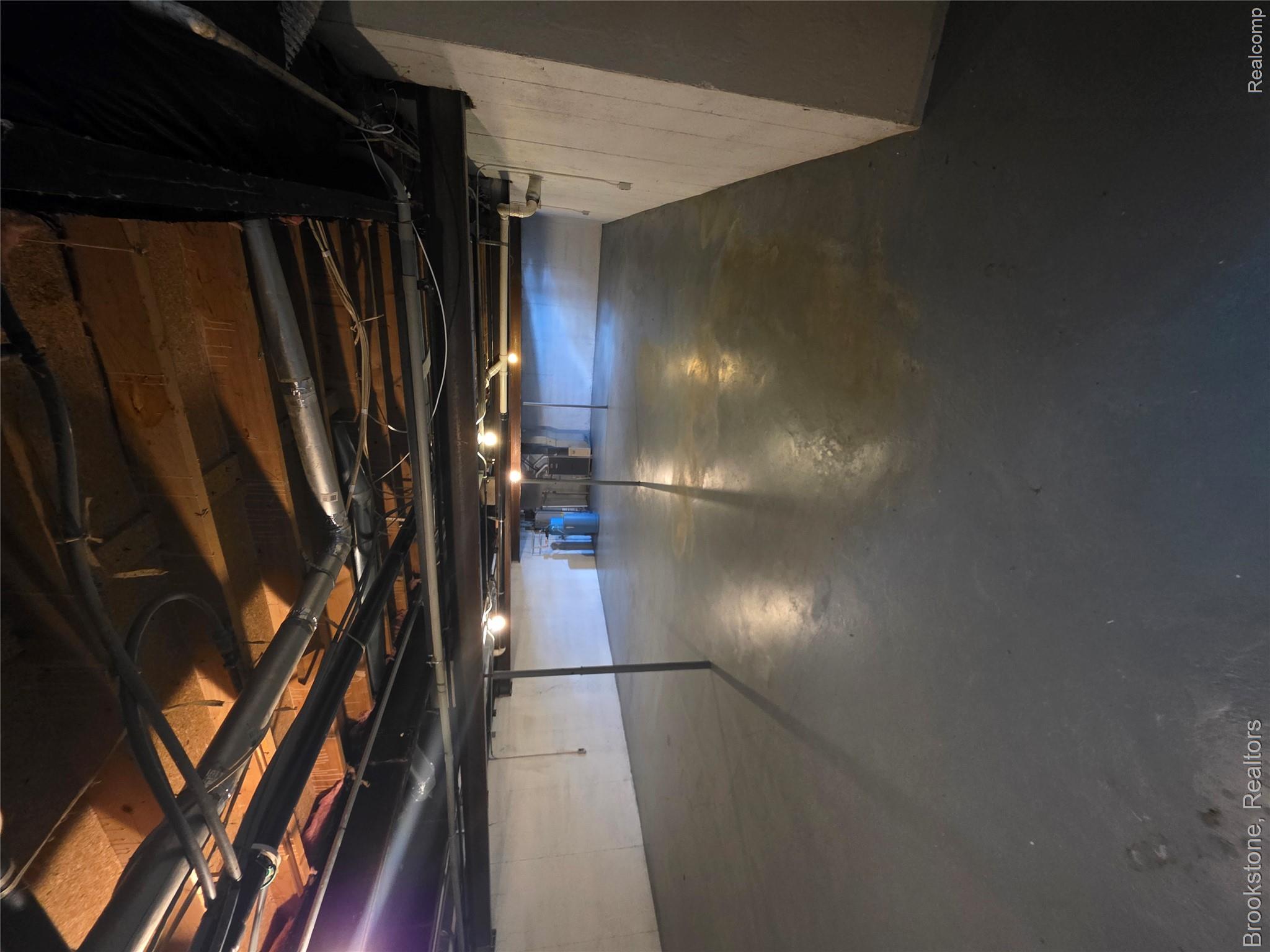4064 East Wilson Road Clio, MI 48420 - Photo 23 of 23 Expansive unfinished basement featuring a painted concrete floor, exposed ceiling joists, white-painted foundation walls, and visible utility lines