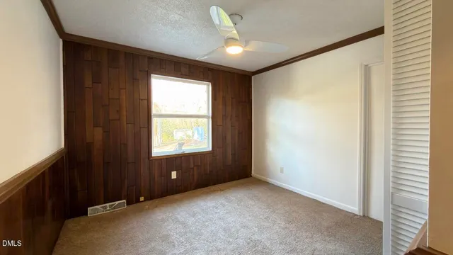an empty room with closet and a chandelier fan