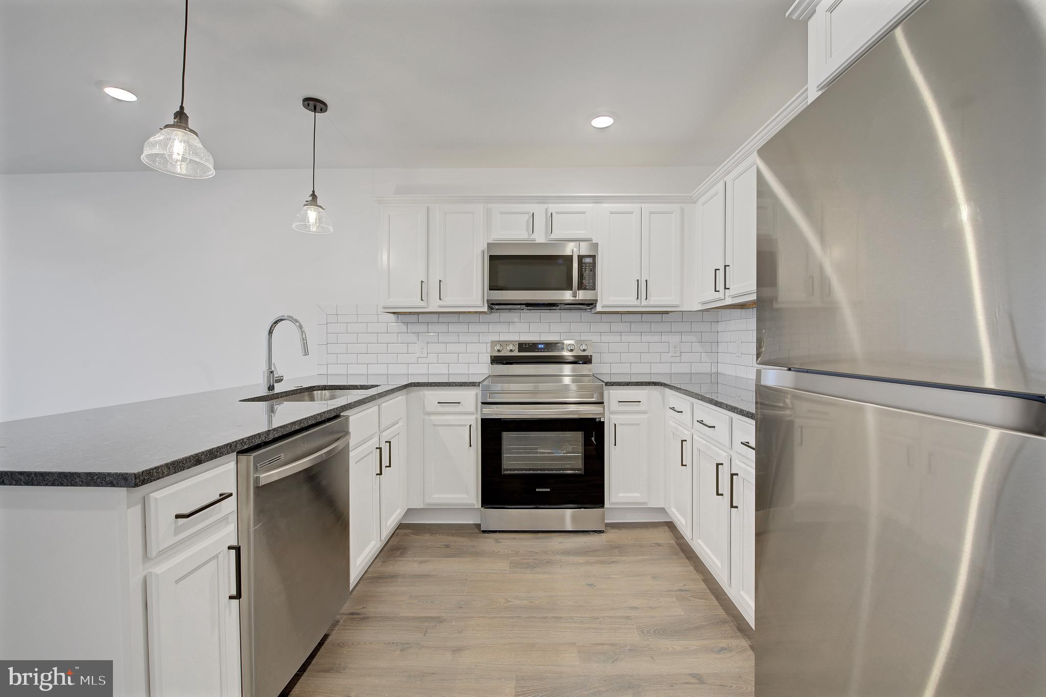 6649 Ridge Avenue, Unit C207 Philadelphia, PA 19128 - Photo 3 of 10 a kitchen with white cabinets and stainless steel appliances