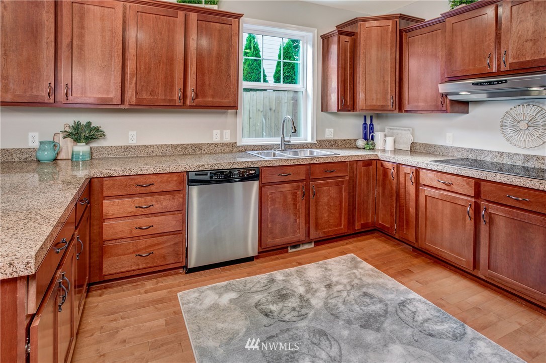 6709 Southeast 2nd Place Renton, WA 98059 - Photo 14 of 25 a kitchen with granite countertop wooden cabinets a sink and dishwasher