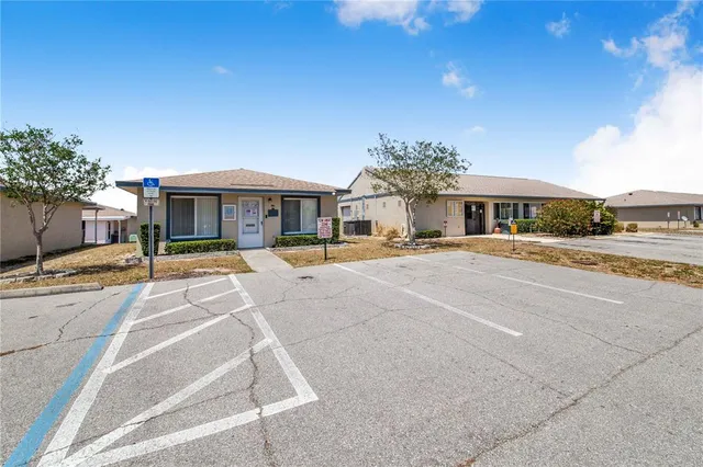 a view of a building with a yard and table and chairs under an umbrella