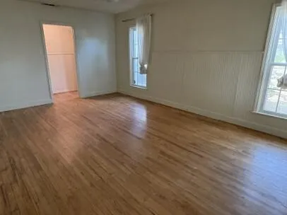 an empty room with wooden floor and windows