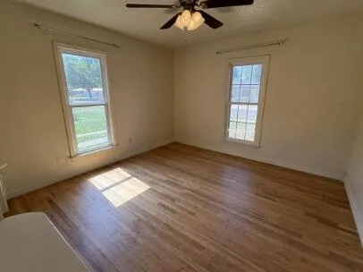 a view of an empty room with wooden floor and a window