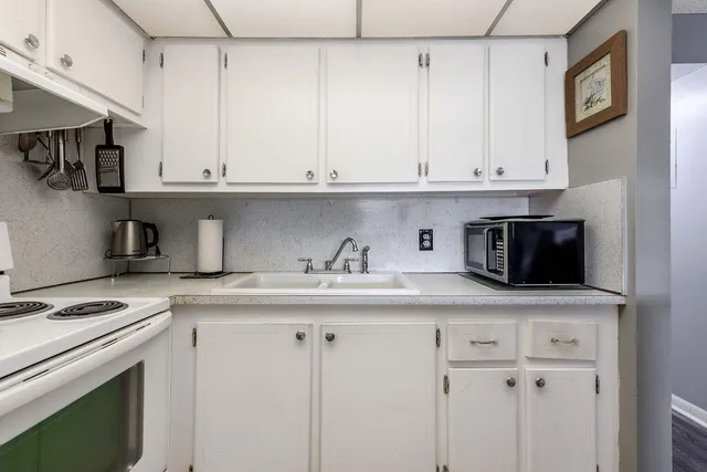 a kitchen with stainless steel appliances granite countertop a sink a stove and white cabinets