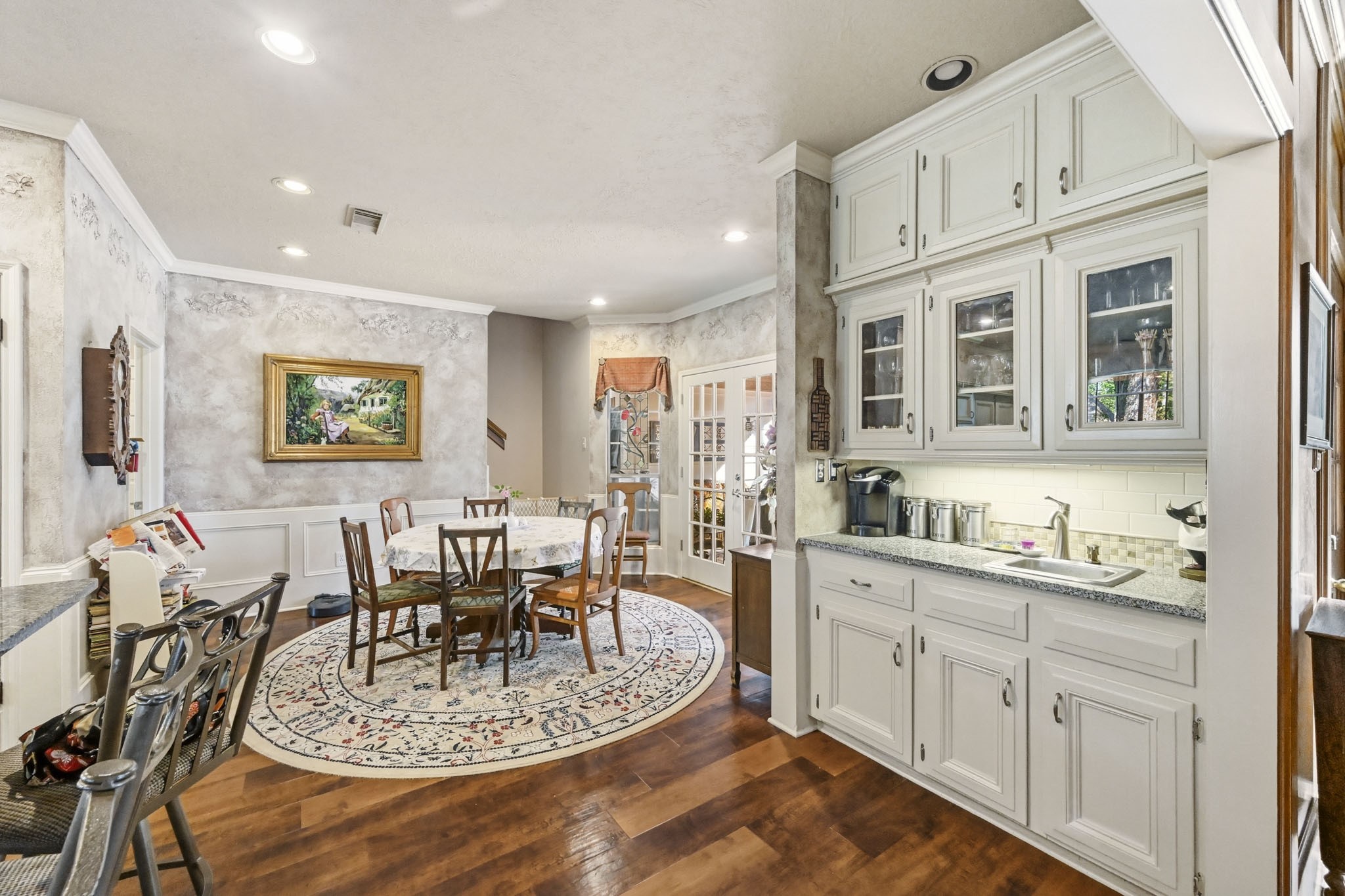 16030 Rudgewick Lane Spring, TX 77379 - Photo 14 of 50 A small wet bar adds a second sink in the kitchen. Sellers enjoy their coffee bar here, with glass front cabinet for glassware. The breakfast area can accommodate a large table with 7 chairs where friends and family sit together for meals, games and fun conversations. The back stairs lead to the game room and upstairs bedrooms.