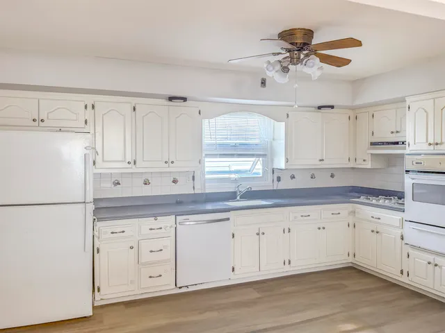 a kitchen with granite countertop white cabinets white appliances and sink