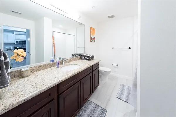 a bathroom with a granite countertop double vanity sink and mirror