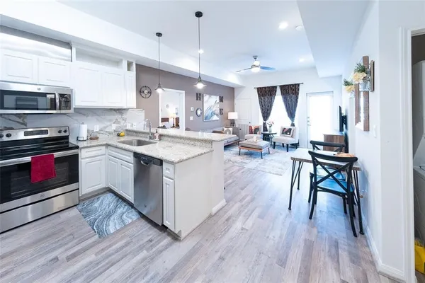 a kitchen with stainless steel appliances granite countertop wooden floors stove top oven and cabinets