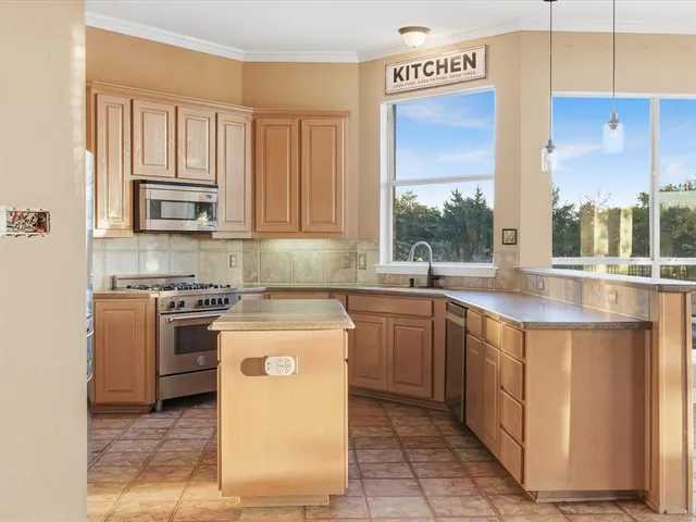 a kitchen with stainless steel appliances granite countertop a stove a sink and a microwave