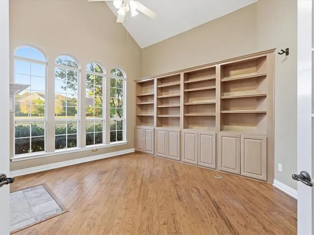 a view of an empty room with a window and wooden floor