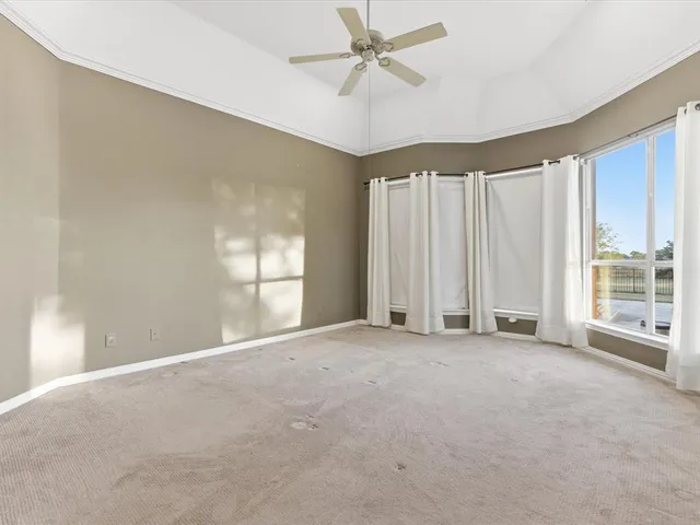 an empty room with windows and ceiling fan