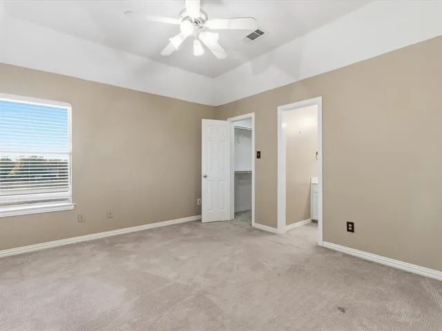 an empty room with chandelier fan and windows