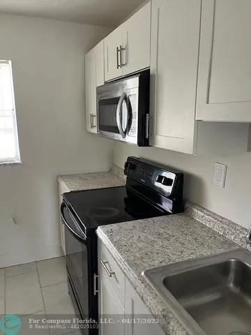 a kitchen with granite countertop white cabinets stainless steel appliances and a window