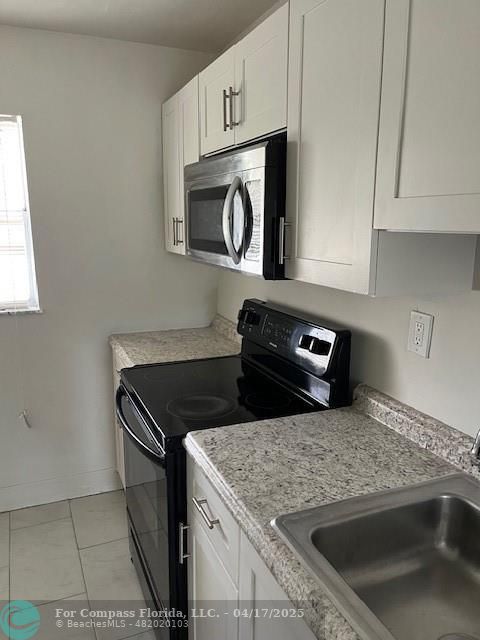 1401 Northwest 45th Street, Unit 4 Deerfield Beach, FL 33064 - Photo 19 of 24 a kitchen with granite countertop white cabinets stainless steel appliances and a window