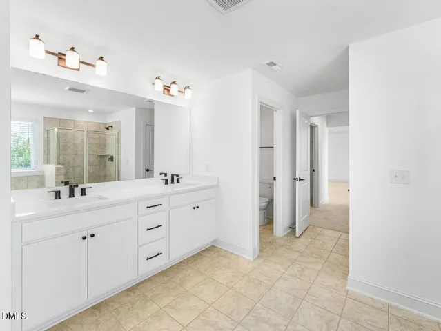 a spacious bathroom with a double vanity sink a mirror and a shower