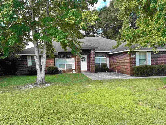 a view of a house with a yard and large tree