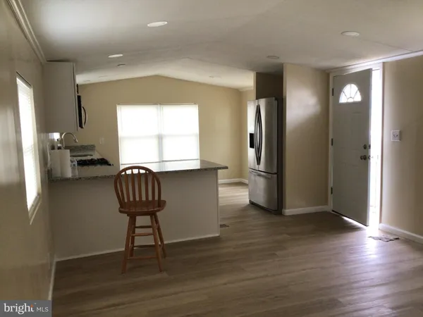 a kitchen with granite countertop a refrigerator and a wooden floor
