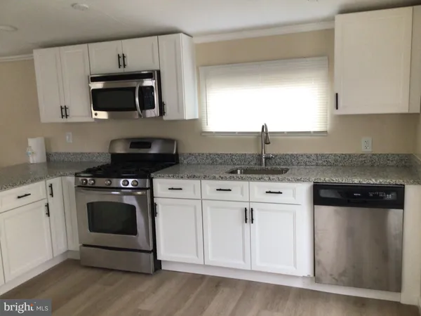 a kitchen with granite countertop white cabinets and stainless steel appliances