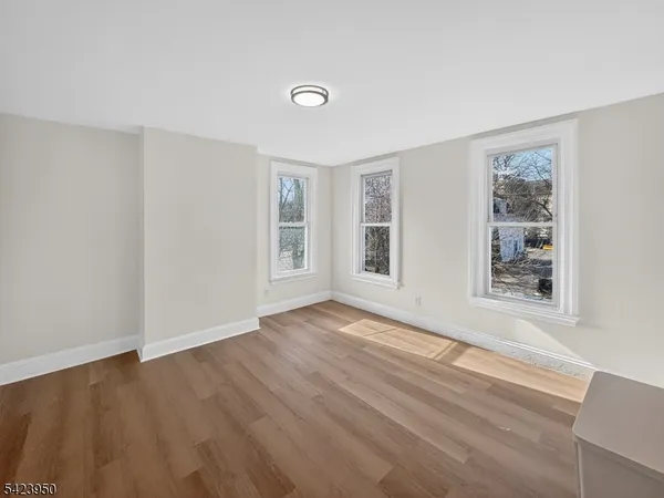 a view of an empty room with wooden floor and window