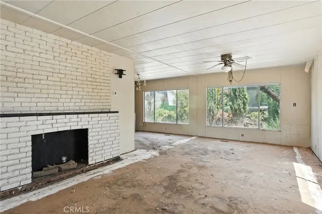 an empty room with windows and fireplace