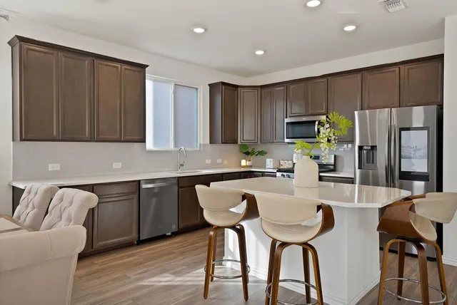 a kitchen with granite countertop a table chairs microwave and refrigerator