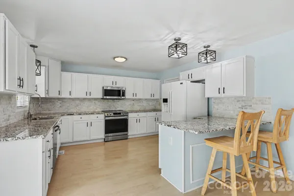 a kitchen with stainless steel appliances granite countertop a stove refrigerator sink and cabinets